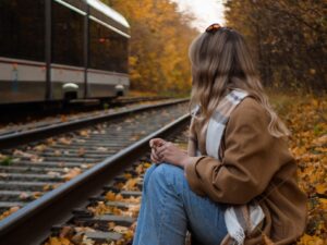 A woman sitting on a train track next to a train