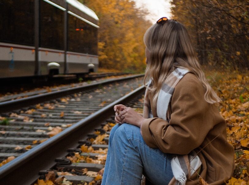 A woman sitting on a train track next to a train